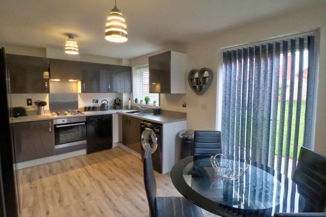 A second view of the kitchen shows the stylish dining area. The room also features integrated appliances, including a four-burner gas hob, oven and extractor, dishwasher and space and plumbing for a washing machine and large fridge freezer. French doors lead out to the garden.