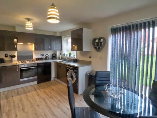 A second view of the kitchen shows the stylish dining area. The room also features integrated appliances, including a four-burner gas hob, oven and extractor, dishwasher and space and plumbing for a washing machine and large fridge freezer. French doors lead out to the garden.