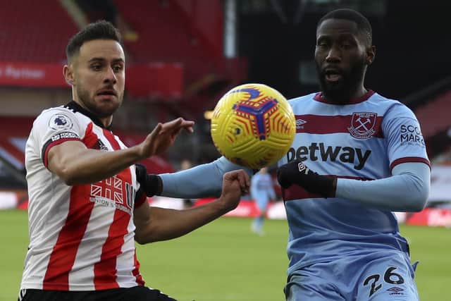 Sheffield United's George Baldock, left, duels for the ball with West Ham's Arthur Masuaku (Cath Ivill/Pool via AP)