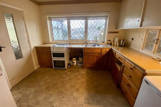 Here is the bungalow's kitchen, which has wall and base units, with worktops over, incorporating a one-and-a-half bowl sink drainer and mixer tap, an electric cooker and radiator.
A door leads to the hallway, while there is a uPVC window to the back of the property.