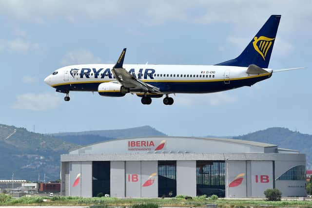 A Ryanair Boeing 737-8AS aircraft flies over an Iberia hangar as it lands at El Prat airport in Barcelona on July 1, 2022. - Nine flights to and from Spain were cancelled on July 1 and dozens of others delayed due to a strike by cabin crew at low-cost airlines Ryanair and EasyJet. The strike over pay and working conditions comes as European schools are breaking up for the summer. (Photo by Pau BARRENA / AFP) (Photo by PAU BARRENA/AFP via Getty Images)