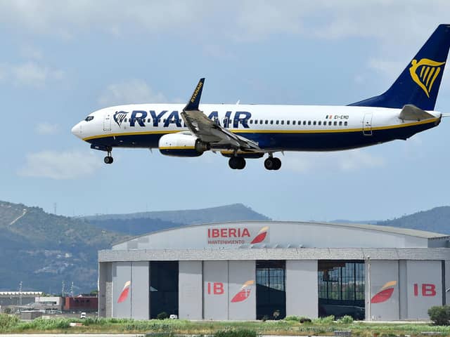 A Ryanair Boeing 737-8AS aircraft flies over an Iberia hangar as it lands at El Prat airport in Barcelona on July 1, 2022. - Nine flights to and from Spain were cancelled on July 1 and dozens of others delayed due to a strike by cabin crew at low-cost airlines Ryanair and EasyJet. The strike over pay and working conditions comes as European schools are breaking up for the summer. (Photo by Pau BARRENA / AFP) (Photo by PAU BARRENA/AFP via Getty Images)