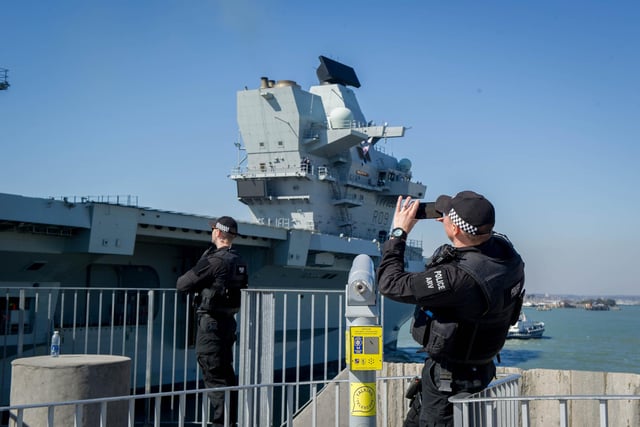 A policeman takes a picture of HMS Prince of Wales as she sails past the Round Tower in Old Portsmouth