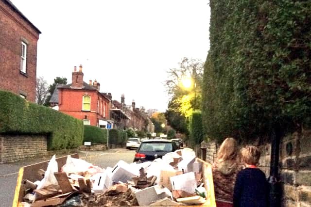 Children squeezing by a skip left on the pavement.