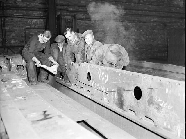 Men checking the plans for a hopper before welding, 1958.
