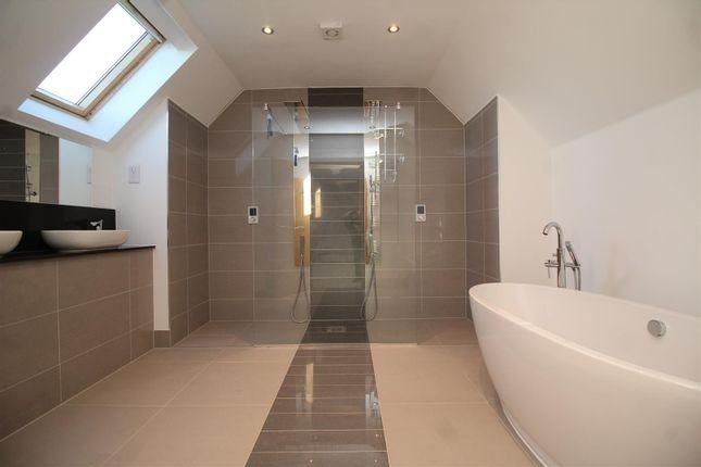 A gorgeous master en-suite bathroom fitted with dual wash basins, a standing bath, and a walk-in shower area with two showers and glass screening