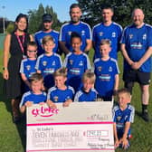 Ellie Matthews receives a cheque from the young footballers