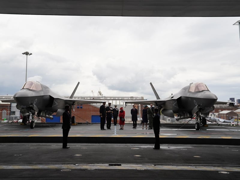 Queen Elizabeth II (centre) going on to the flight deck, with a pair of F-35B Lightning II aircraft on either side, during a visit to HMS Queen Elizabeth at HM Naval Base, Portsmouth, ahead of the ship's maiden deployment. The visit comes as HMS Queen Elizabeth prepares to lead the UK Carrier Strike Group on a 28-week operational deployment travelling over 26,000 nautical miles from the Mediterranean to the Philippine Sea. Picture date: Saturday May 22, 2021. PA Photo. See PA story ROYAL Carrier. Photo credit should read: Steve Parsons/PA Wire