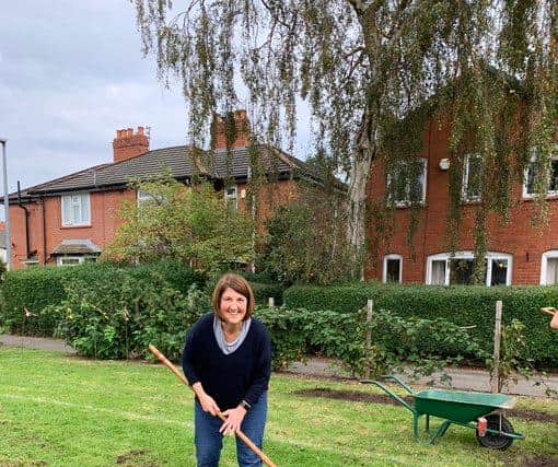 Joanna Midgley hard at work with a rake and wheelbarrow