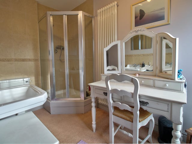 Comprising of corner shower unit, WC and wash basin. Part tiled walls, shaver point and wall mounted vertical radiator.