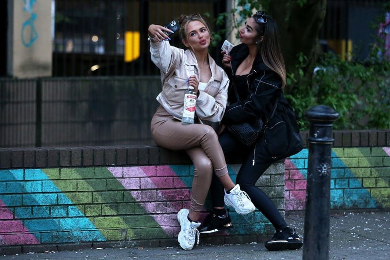 Two girls take a selfie while drinking alcohol on a wall in Manchester's Northern Quarter on April 16, 2021 in Manchester, England (Photo by Charlotte Tattersall/Getty Images)