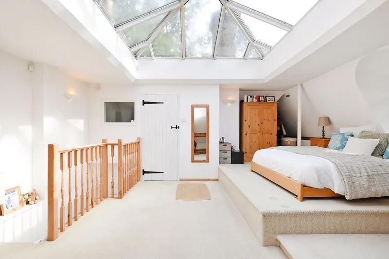 On the first floor, there is a stunning open plan studio-style master bedroom. It is light and airy, spacious, and a split-level design, with exposed brick and stonework, set against white decor. There's an arched front window, two rear windows and a larger size roof lantern.