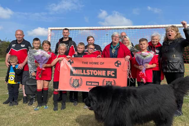 Players and volunteers from Millstone FC stand with the club's mascot, Murphy.