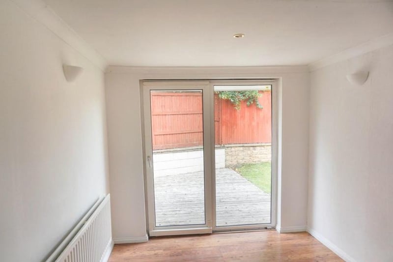 Airy spacious neutrally decorated room with wall mounted lights and ceiling spotlights, low maintenance flooring and patio doors opening onto the garden and patio decking providing a lovely social space to bring the outside in