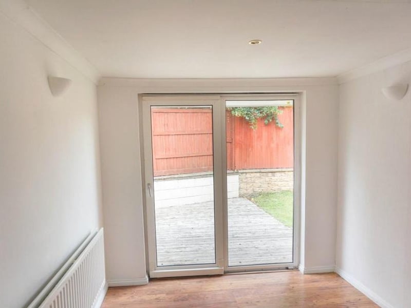 Airy spacious neutrally decorated room with wall mounted lights and ceiling spotlights, low maintenance flooring and patio doors opening onto the garden and patio decking providing a lovely social space to bring the outside in
