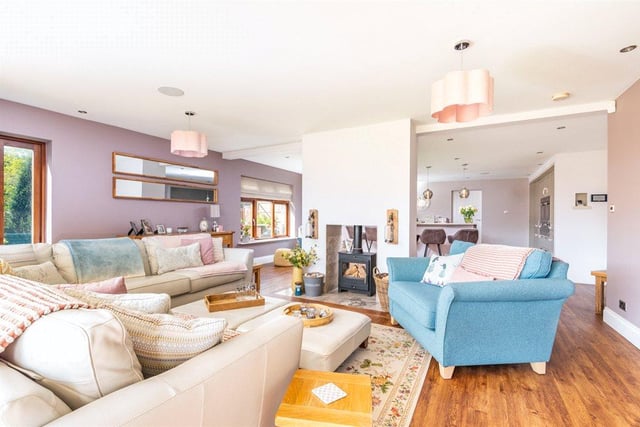 The property boasts five reception rooms in total, including this cosy open plan family room complete with hardwood floors, overhead spotlights and a woodburner at its heart.