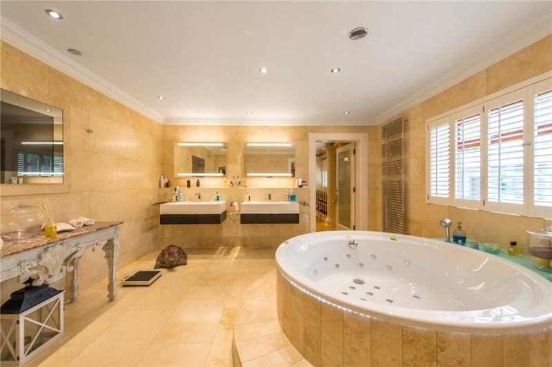 The principal bedroom en-suite has a round spa bath, limestone walls and floor, a plasma screen television, double shower cubicle, bidet, WC and two basins with cabinets over and drawers below.