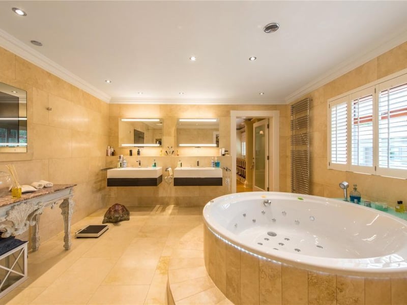The principal bedroom en-suite has a round spa bath, limestone walls and floor, a plasma screen television, double shower cubicle, bidet, WC and two basins with cabinets over and drawers below.