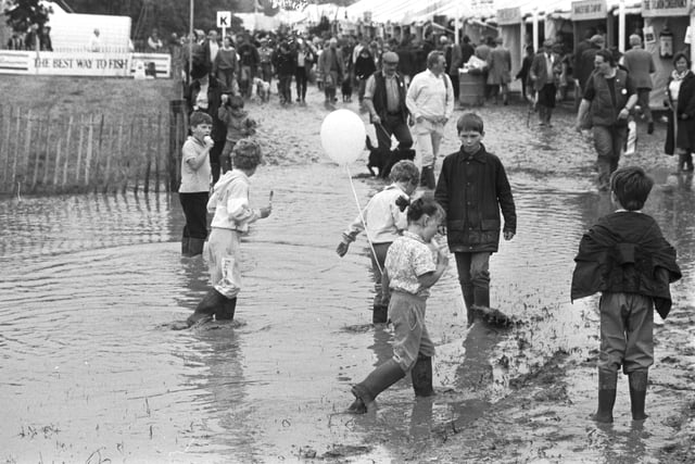 Children enjoy the puddles and mud at a rather wet Scottish Game Fair, held in Kelso, July 1988.