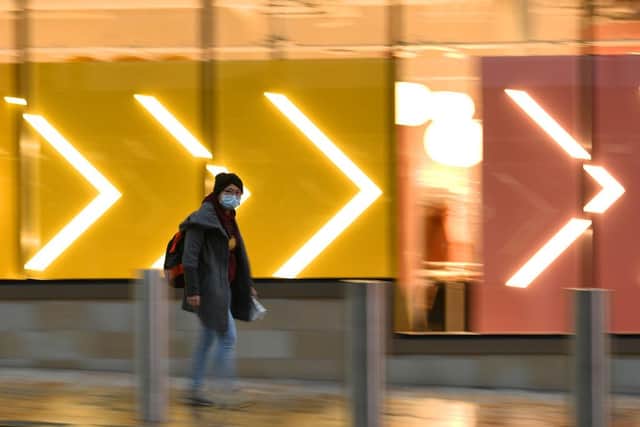 A pedestrian wearing a protective face covering walks past a store in central Sheffield (Photo by OLI SCARFF/AFP via Getty Images)