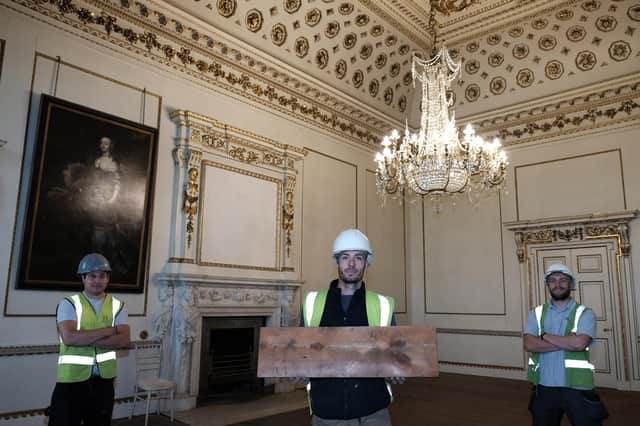 Workers Richard Holden, left, Joe Hutchinson and Jack Richmond with the board from 1830 they found in the roofspace above  the Van Dyck room at Wentworth Woodhouse