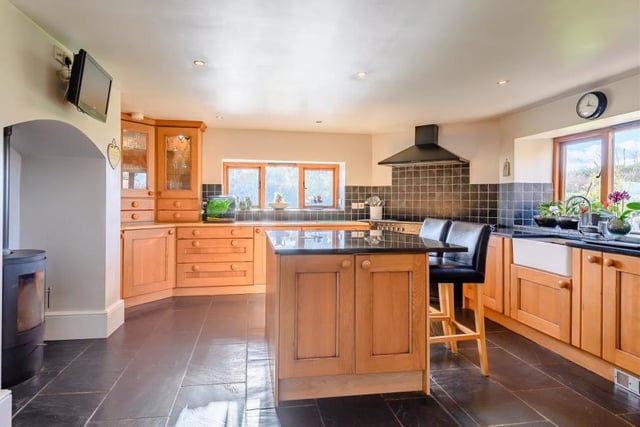 The impressive kitchen/breakfast room features a fireplace housing a log burner, an inset Belfast sink with mixer tap and integrated fridge and dishwasher. A range of cabinets, cupboards, drawers and granite worktops are complemented by a central island. Tiled floors and ceiling spotlights top things off.
