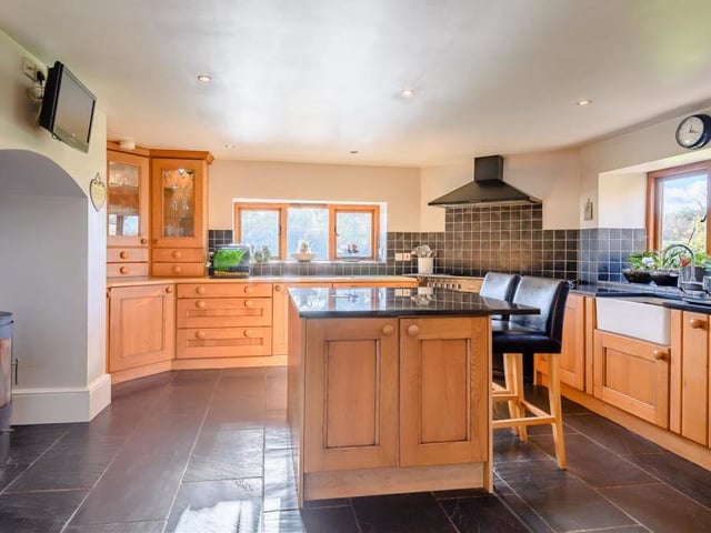 The impressive kitchen/breakfast room features a fireplace housing a log burner, an inset Belfast sink with mixer tap and integrated fridge and dishwasher. A range of cabinets, cupboards, drawers and granite worktops are complemented by a central island. Tiled floors and ceiling spotlights top things off.