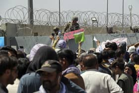 A US soldier holds a sign indicating a gate is closed as hundreds of people gather near an evacuation control checkpoint on the perimeter of the Hamid Karzai International Airport, in Kabul, Afghanistan on August 26