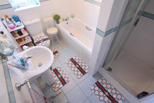 The family bathroom is busy and attractive. With its tiled floor, it features a panelled bath, step-in shower enclosure, push-button WC and wash hand basin