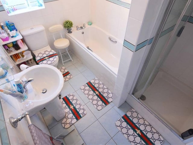 The family bathroom is busy and attractive. With its tiled floor, it features a panelled bath, step-in shower enclosure, push-button WC and wash hand basin