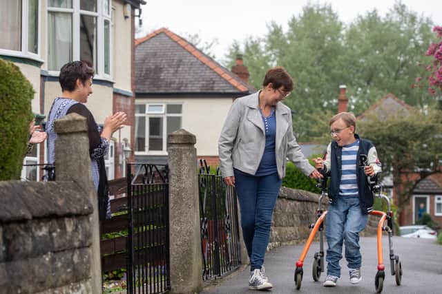 Tobias Weller, who has cerebral palsy, is cheered on by neighbours as he walks along the street outside his home in Beauchief, Sheffield, as he strives to complete a lockdown marathon for charity (Pic: Joe Giddens/PA)