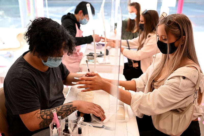 Customers sit behind protective screens at a nail bar in Liverpool, as salons reopen for beauty treatments.