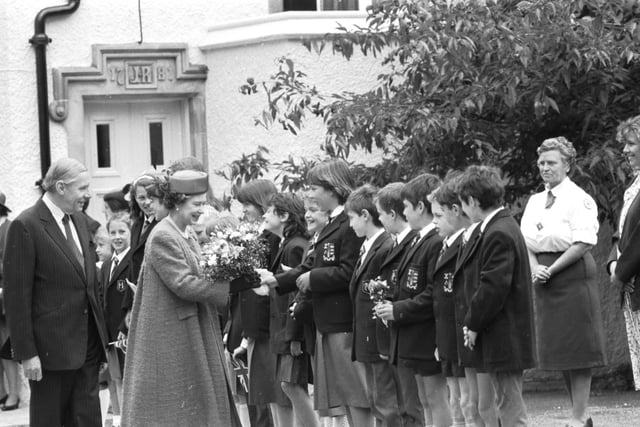 Queen Elizabeth II receives flowers from school children during a visit to Peebles in June 1988.