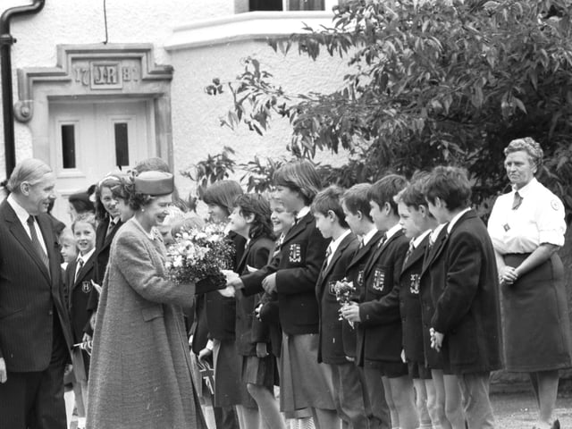 Queen Elizabeth II receives flowers from school children during a visit to Peebles in June 1988.