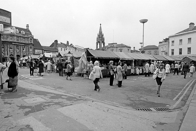 A busy market place full of stalls and shoppers