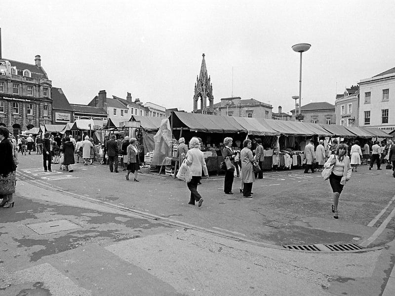 A busy market place full of stalls and shoppers