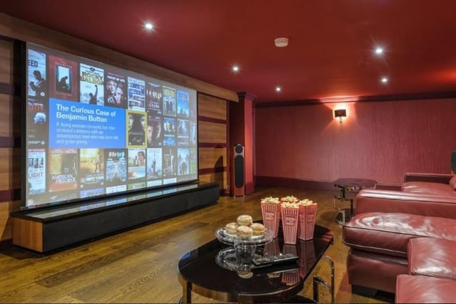 The cinema room has panelled walls, a projector screen and bespoke leather furniture for a luxurious viewing experience.