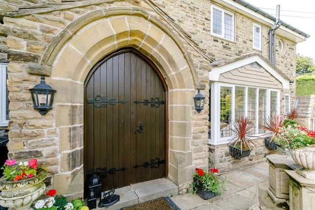 The solid oak front door leads to a grand entrance hall with stone flooring, oak wood panelling and exposed oak beams.