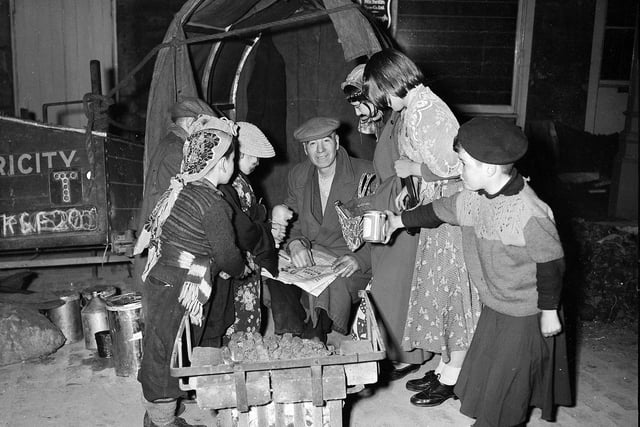 Halloween guisers visit a night watchman working in the Grassmarket in October 1957.