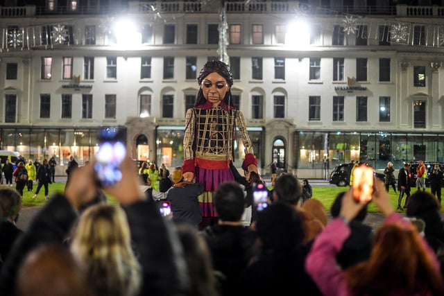 Little Amal, the puppet representing a displaced Syrian child, is seen arriving in George Square.