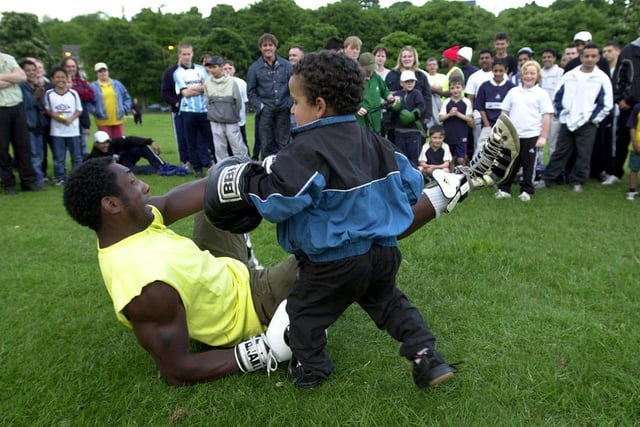 Take it easy on the man he's down!  4 years-old Alaa Al-Afif takes the fight to Sheffield champion boxer Johnny Nelson during the boxer's outdoor boxing exibition in Firth Park, May 2001