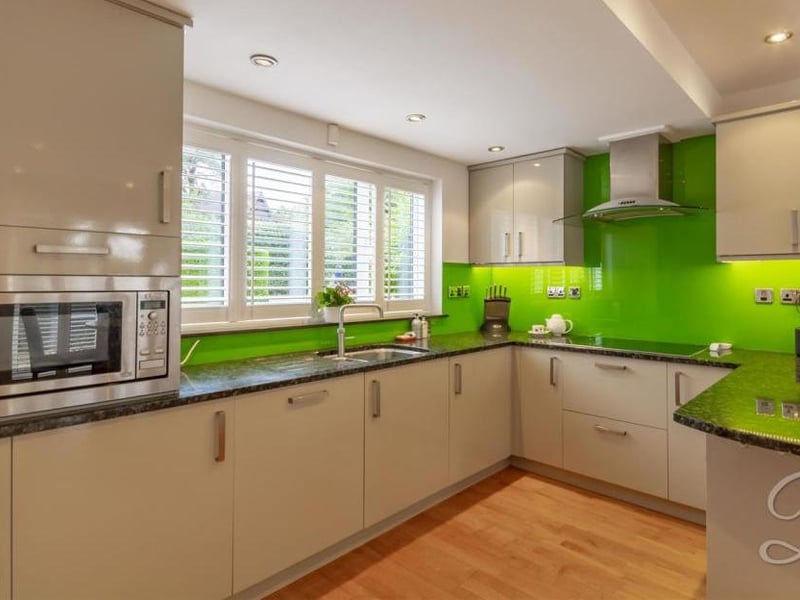 Another look at the kitchen, with modern cabinets and units, granite work-surface, stainless-steel bowl, extractor fan and integrated appliances. There are three central-heating radiators, a window to the front and patio doors that lead to the back garden.