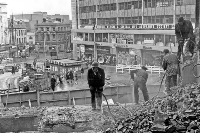 Arundel Gate and Castle Square in Sheffield city centre during the construction of the Hole in the Road subway and roundabout in February 1967. Workers are shown reducing the size of Walsh's Department Store to allow for road widening.