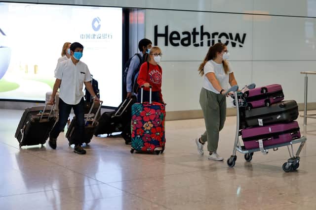 Passengers wearing PPE (personal protective equipment) arrive at Terminal 2 of Heathrow airport (TOLGA AKMEN/AFP via Getty Images)