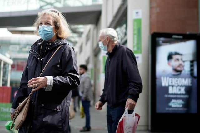 People wear face masks as they shop  (Photo by Christopher Furlong/Getty Images)
