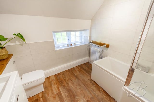 A newly fitted bathroom suite comprises bath with an overhead shower and screen, wc and vanity unit containing hand basin.