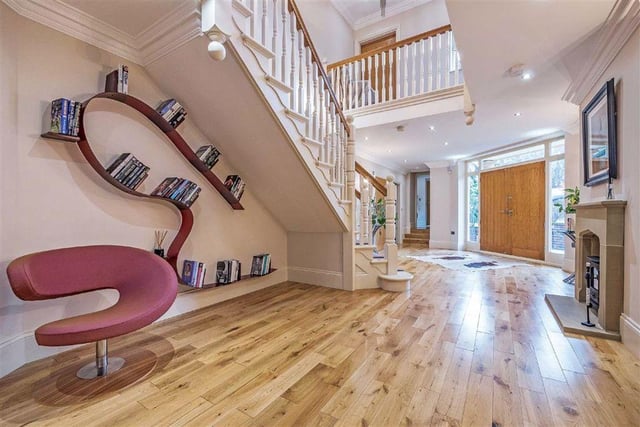 The spacious entrance hall is bright and airy, and benefits from wooden floors and a stone fireplace, with room for a seating area beneath the stairs.