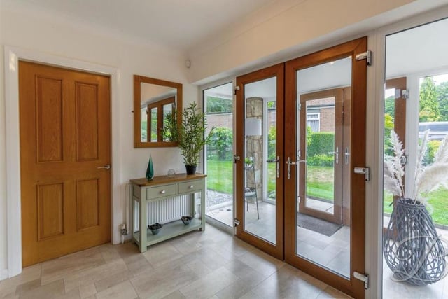 A spacious entrance hallway with double doors, a central-heating radiator and a cupboard for storage. A carpeted staircase leads to the first floor.