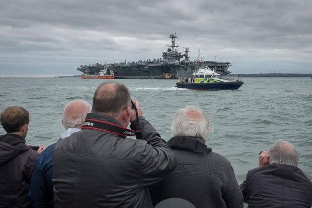 Sightseers take photographs of the US warship USS Harry S. Truman, anchored in the Solent on October 8, 2018 near Portsmouth.