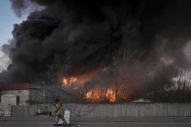 Ukrainian servicemen carry containers backdropped by a blaze at a warehouse after a bombing on the outskirts of Kyiv, Ukraine, Thursday, March 17, 2022. Russian forces destroyed a theater in Mariupol where hundreds of people were sheltering Wednesday and rained fire on other cities, Ukrainian authorities said, even as the two sides projected optimism over efforts to negotiate an end to the fighting. (AP Photo/Vadim Ghirda)